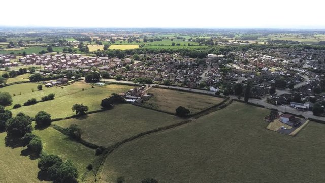 Aerial view, slow panning move. Town in cheshire. Housing development. Plains and grassland.