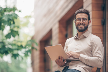 Smiling man with laptop outdoors