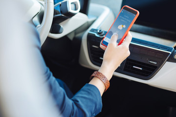 Warm and sunny. Modern smartphone being in hand of a nice professional female driver while showing...