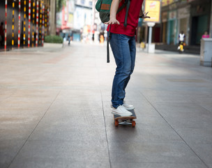 Fototapeta premium Skateboarder use smartphone sit on skateboard on city street
