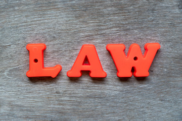 Colorful plastic alphabet in word law on wood background