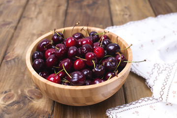 cherry in a wooden plate on a wooden background. Copy space,