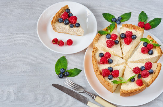 Slice of cheesecake with fresh berries on the white plate - healthy organic dessert. Classic New York cheese cake decorated with blueberries, raspberries and mint. Top view with copy space for text