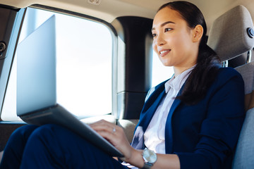 Internet connection. Delighted positive woman using the Internet connection while working from the car on her laptop