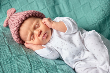 Baby girl lying on her back covering her ears. Newborn baby closes her ears and sleeping.
