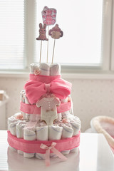 Newborn gift concept. Decorated cake of diapers indoor.