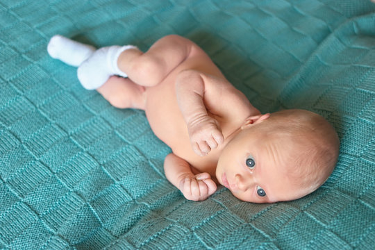 Naked newborn baby. Cute caucasian baby with big blue eyes lying on woolean clothes.