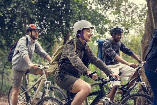 Group Of Friends Ride Mountain Bike In The Forest Together