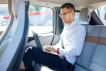 Professional businessman. Smart successful businessman using his laptop while working from the car