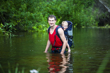 The daddy carries the child during a flood in the jungle.