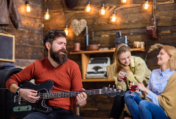 Bearded man singing serenade for his wife, love and romance concept. Couple celebrating anniversary or St. Valentine Day. Family spending lovely evening together. Man with trendy beard playing guitar