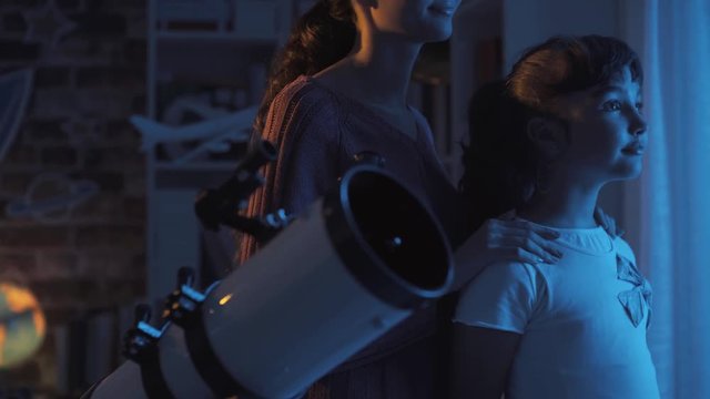 Sisters stargazing together with a professional telescope