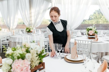 Girl waiter in the restaurant serving the table to prepare for the reception