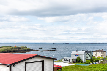 Stykkisholmur, Iceland national country flag with blue, red stripes in wind on cloudy overcast day, cityscape skyline of small fishing village town on Snaefellsnes peninsula, lighthouse