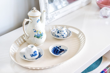 Closeup of table shelf stand with coffee or afternoon tea cups in home interior, nobody, ceramic porcelain English teapot, plates with blue flower design