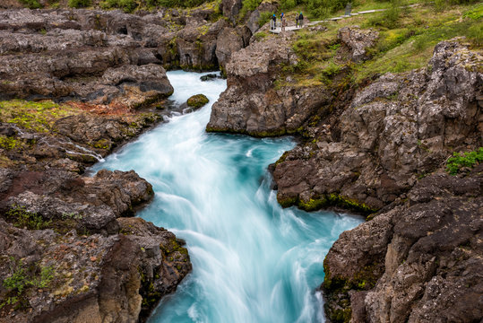 Long exposure smooth colorful blue aqua turquoise water waterfall cascade aerial view down of Hraunfossar Lava Falls in Iceland, landscape view