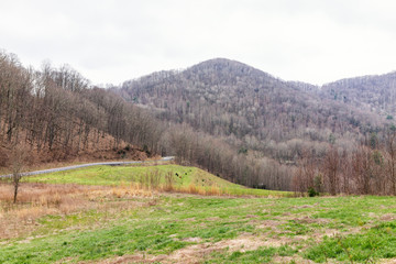 Fototapeta na wymiar Smoky Mountains near Asheville, North Carolina at Tennessee border at winter, spring, clouds, cloudy overcast sky, green grass, highway road