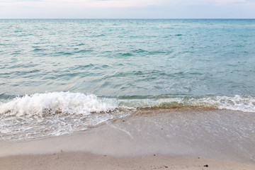 Wave crashing closeup on shore in Sunny Isles Beach, North Miami, Florida during evening sunset with colorful water, wet sand, nobody