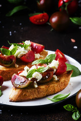 Italian crispy toasted bruschetta with black and brown cherry tomatoes, blue cheese and basil, selective focus