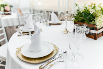 Serving tableware on a table with fresh flowers on a white tablecloth in the restaurant