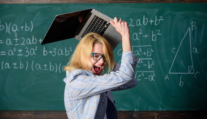 Overstrain of the nervous system. Teacher woman raising laptop above herself ready to destroy. She...