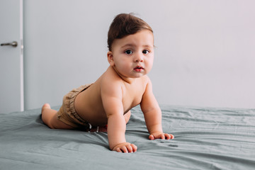 Beautiful baby crawling on the bed in the room, family lifestyle