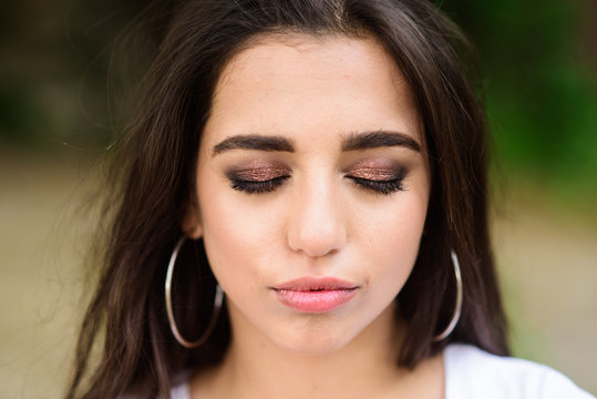 Lady relaxed face make up close eyes with shimmering eyeshadows. Make up concept. Girl attractive gorgeous brunette middle eastern appearance with make up close up. Girl wear metallic earrings