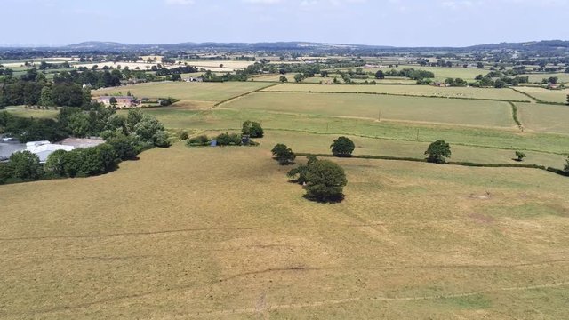 Aerial view, pedestal down move. Plains, grass, grassland in Cheshire. Cars on road in background