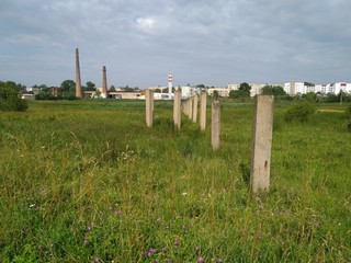 a row of concrete poles with a factory in the background