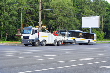 The tow truck is carrying a broken shuttle bus