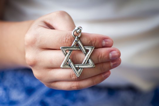 Young woman's hand holding a David Star ("Magen David") key chain. The State of Israel, Judaism, Zionism concept image.