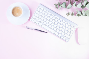 Flat lay home office workspace - white modern keyboard on pink desk with copy space