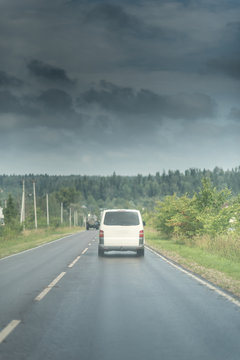 Delivery White Van On The Rural Road Under The Dark Clouds