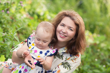 Portrait of happy cheerful mother and daughter in summer garden.