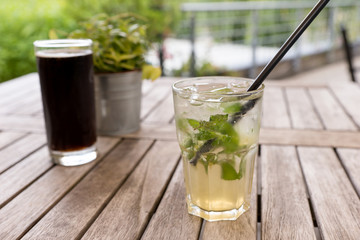 Natural lemonade with lime and mint in glass on wooden table in a outdoor restaurant