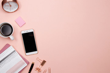 Office table desk with smartphone and other office supplies on pink background. Top view with copy space, flat lay.