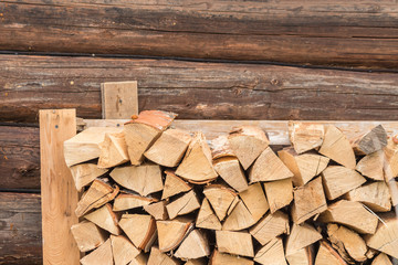stack of firewood on log wall background. outdoor storage of woodpile