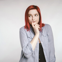 Red haired plus size ordinary woman standing on a neutral grey background. Emotional portrait. She...