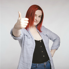 Red haired plus size ordinary woman standing on a neutral grey background. Emotional portrait. She...