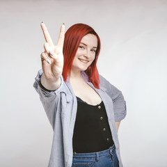 Red haired plus size ordinary woman standing on a neutral grey background. Emotional portrait. She...