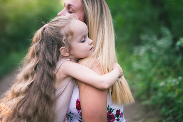 Beautiful young woman and her charming little daughter are hugging
