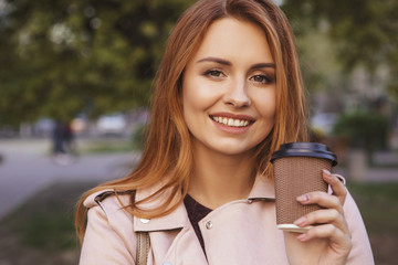 Red haired sexy plus size woman walking on a park. Cold weather, she wears leather jacket. She...
