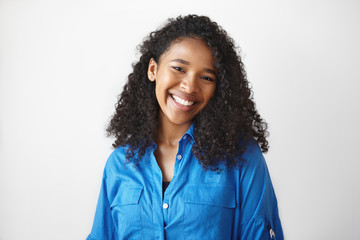 Picture of gorgeous African student girl wearing casual blue shirt rejoicing at good results on...