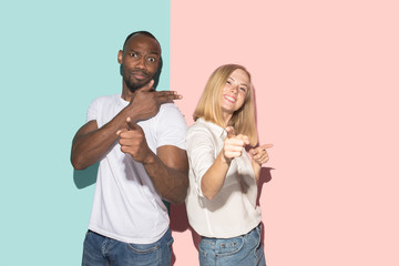 Beautiful female and male portrait on pink and blue studio backgroud. The young emotional couple