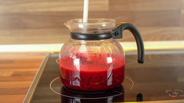 Himbeeren sind entsaftet. Himbeersaft und Gelierzucker werden auf dem Herd gekocht. Umr&uuml;hren und Kochen als Nahaufnahmen mit orginal Sound.