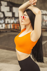 Sexy slim fit brunette woman in sport casual outfit in a skate park. Summer sunny day
