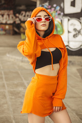 Sexy slim fit brunette woman in sport casual outfit in a skate park. Summer sunny day
