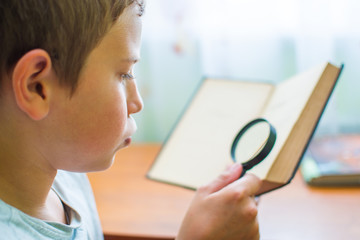 boy reading a book with a magnifying glass