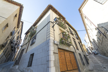 Medieval cobbled and stepped street with flowery balconies and public lighting lamps in the city of Toledo. Spain