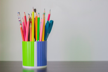 colored pencils and pens in a glass on the table